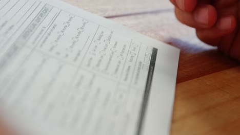 Close-up-of-businessman-sitting-at-desk-filling-contract