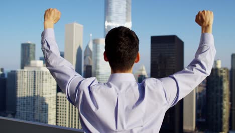 asian male celebrating business success overlooking chicago cityscape