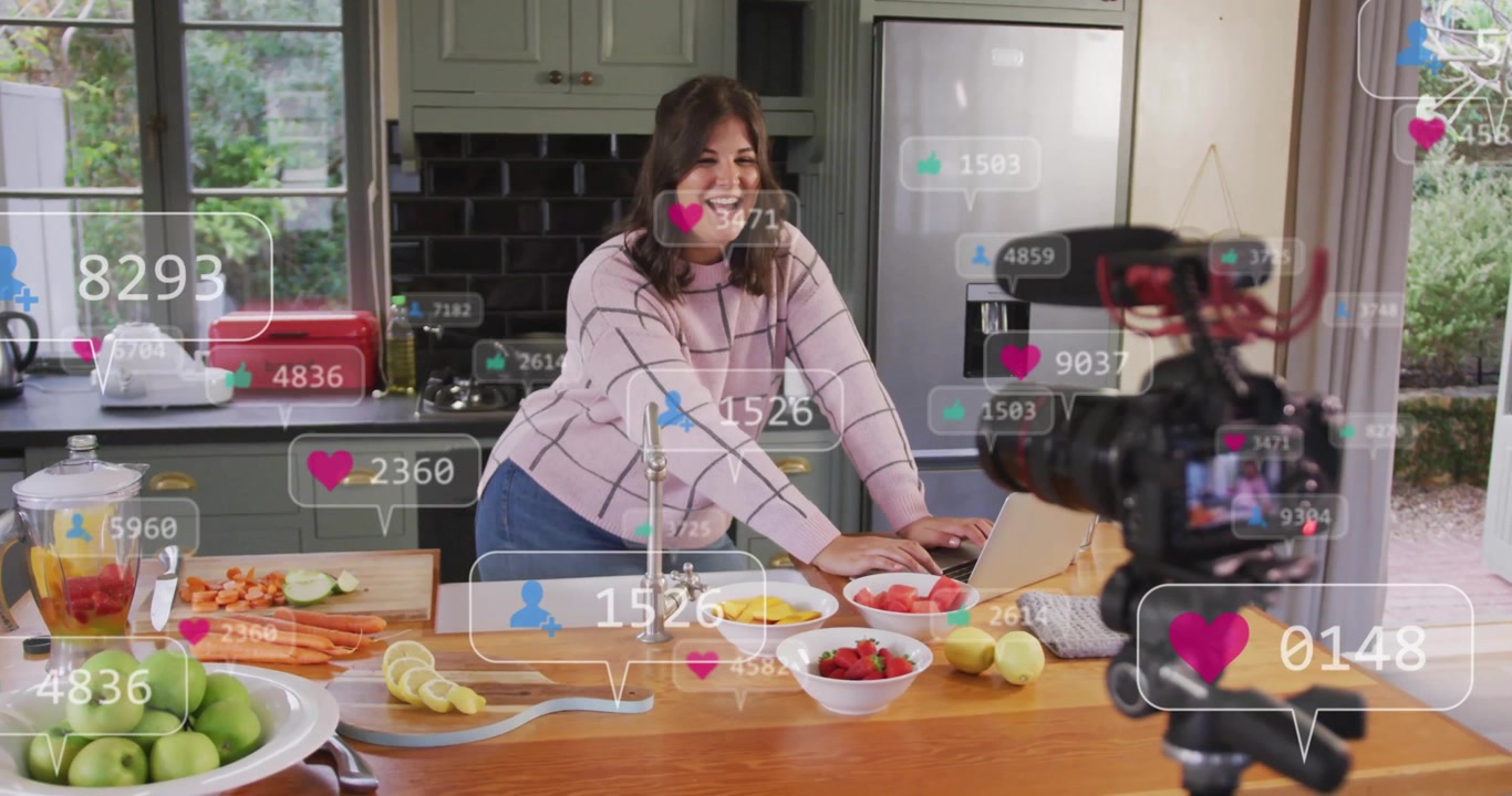 female content creator typing laptop during live cooking activating social icons rising near camera