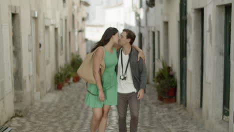 front view of young couple walking along cobble stone road.