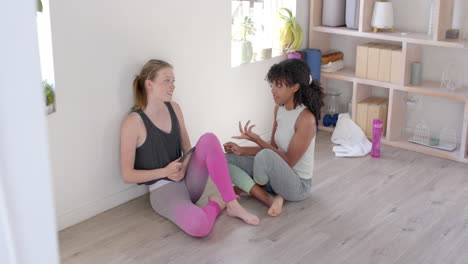 happy diverse women sitting on floor and talking with smartphone, slow motion