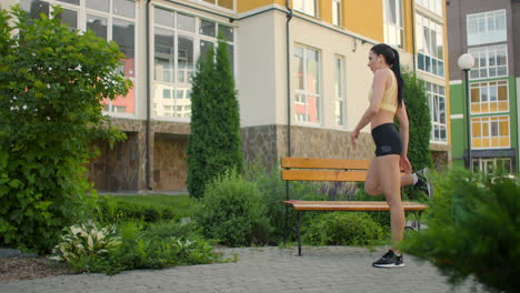 una mujer con auriculares se calienta antes de correr en el parque. enganche después de entrenar estiramiento de piernas