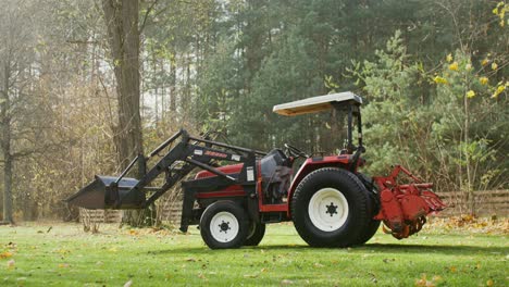 pequeño tractor rojo con cargador en un campo