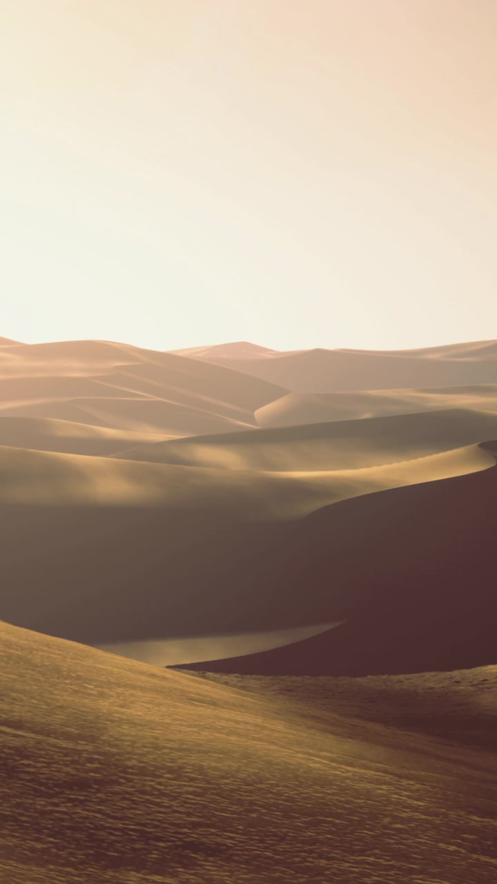Il sole tramonta su dolci colline creando lunghe ombre e un caldo bagliore.