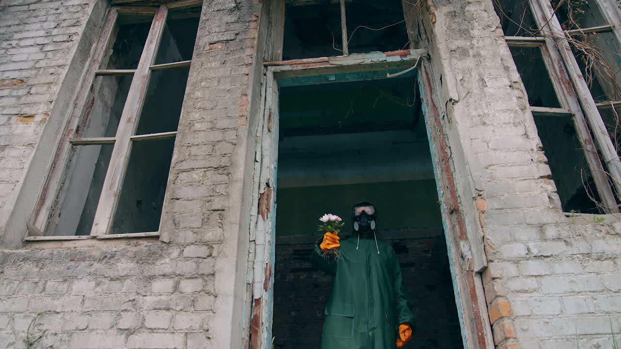 Man in safety suit and goggles. Human in protective uniform planting flowers in dangerous city.