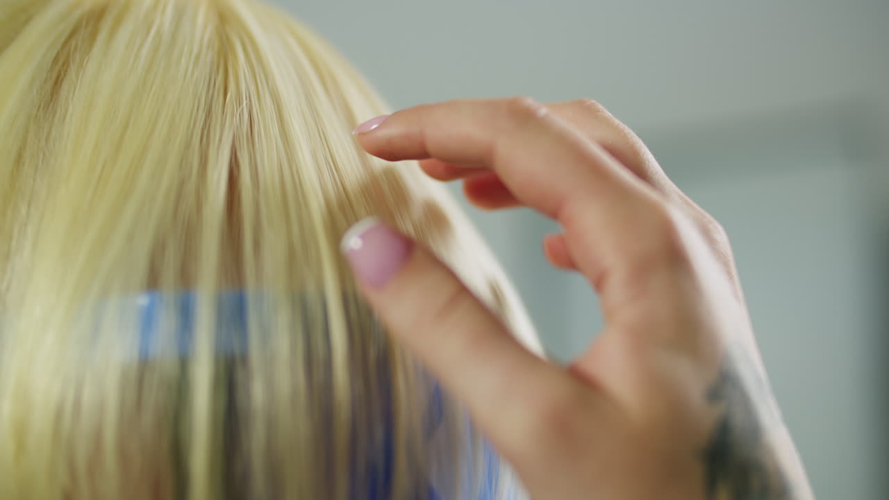 Primer plano de una chica pasándose la mano por el pelo rubio mientras lleva una visera azul
