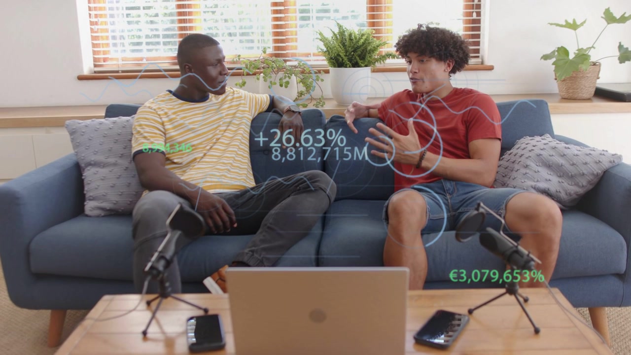 Apresentador da direita iniciando um podcast no sofá, com os apresentadores gesticulando enquanto sobreposições financeiras são atualizadas sobre o laptop.