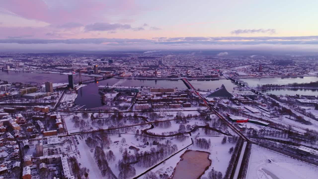 High static drone view of Riga city in winter sunrise, unfrozen Daugava river