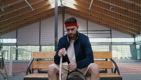 man preparing tennis racket on indoor court