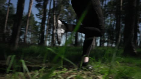 A-woman-in-running-clothes-runs-past-the-camera-in-a-sunlit-forest