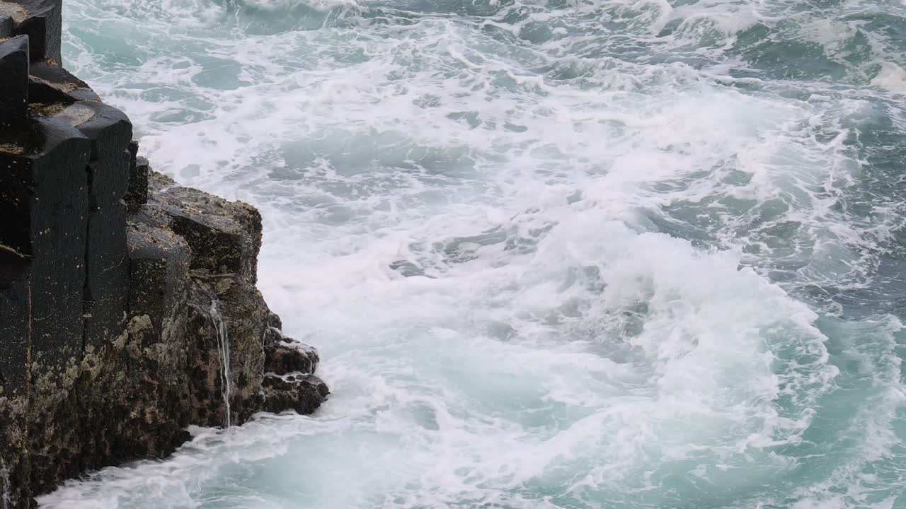 바다의 파도가 바위가 있는 해안선과 충돌합니다.