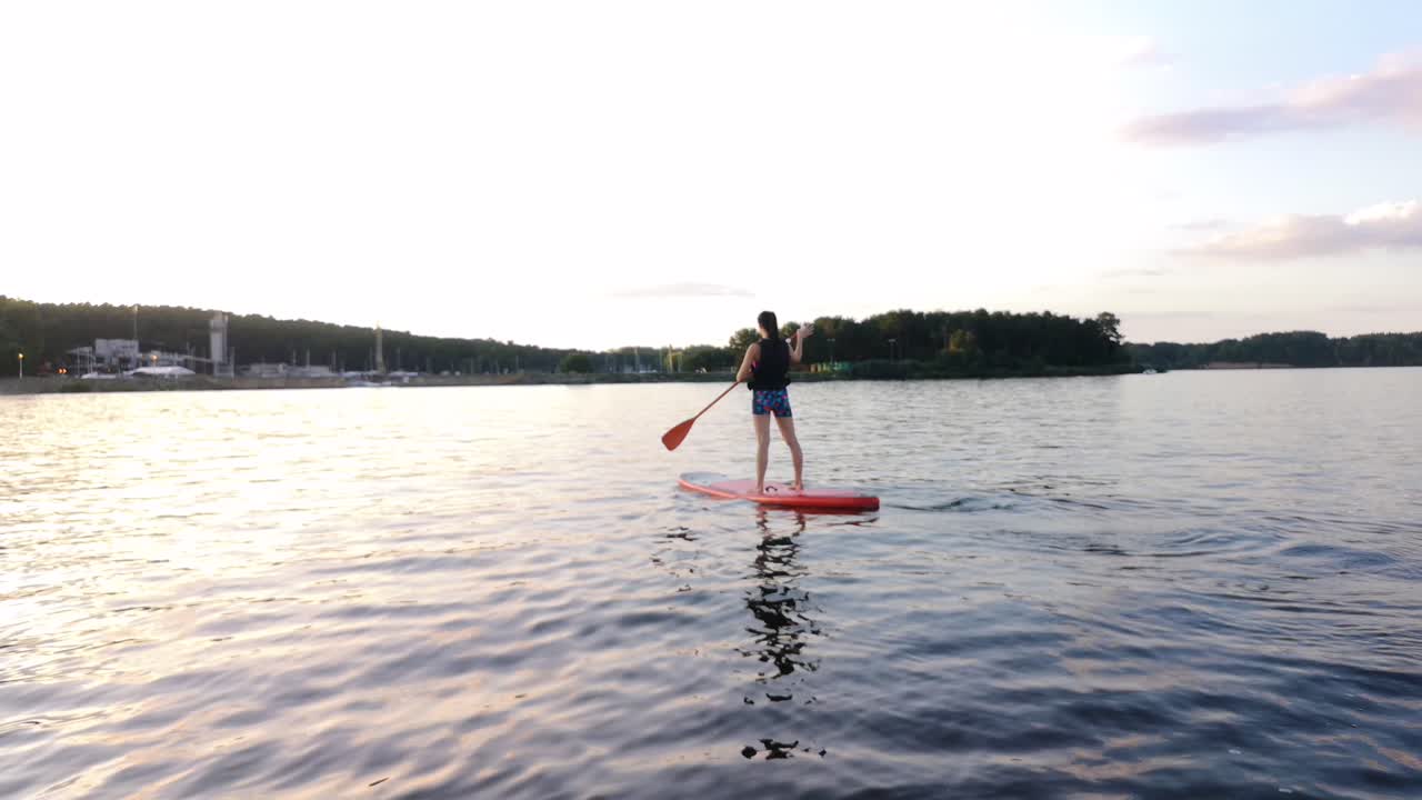 큰 호수에 어린 소녀 패들 보딩이 있습니다