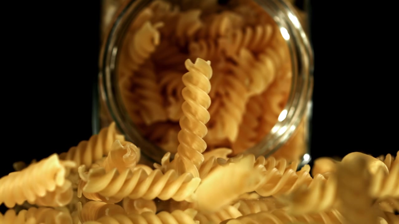 Dry Fusilli Pasta Falling from a Glass Jar in Slow Motion