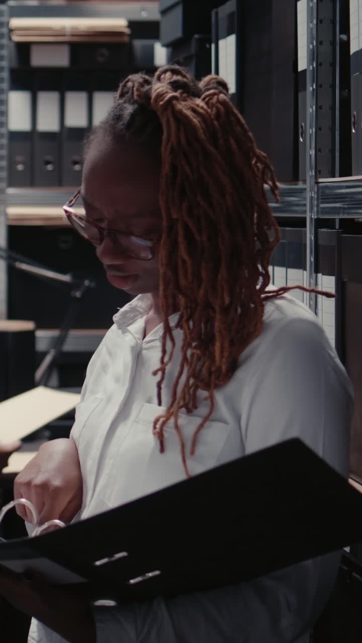 Vertical video: Police officers examining case files for clues in archive
