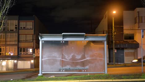 Parada-De-Autobús-De-Vancouver-En-La-Noche-Con-Huellas-En-Vidrio-De-Tres-Personas-Sentadas-En-El-Banco