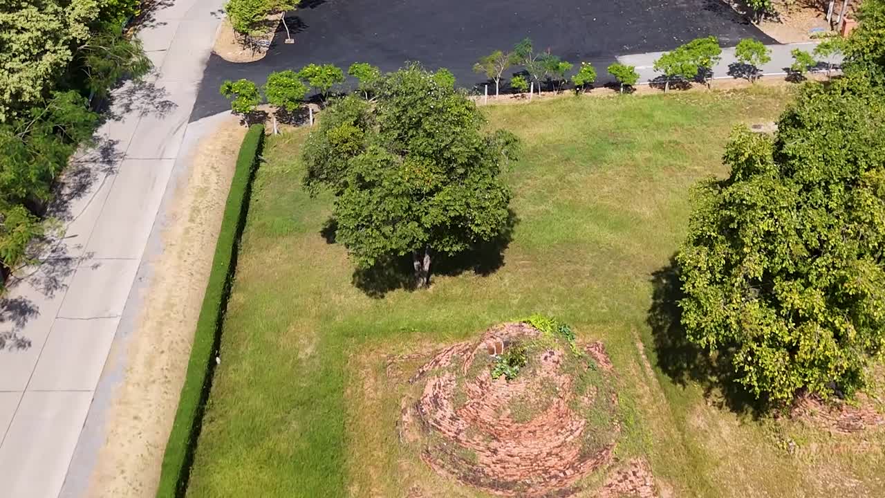 Drone shot of an elephant walking along a road beside historic brick temple ruins