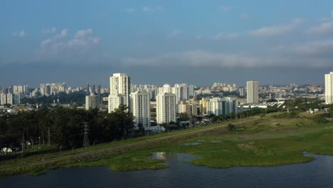 Luftdrohne-Hinterließ-An-Einem-Herbstabend-Eine-LKW--Und-Schwenkaufnahme-Des-Südens-Von-São-Paulo,-Brasilien,-Vom-Künstlichen-Guarapiranga-Stausee-In-Richtung-Des-Stadtteils-Socorro-Mit-Wolkenkratzern-Und-Häusern