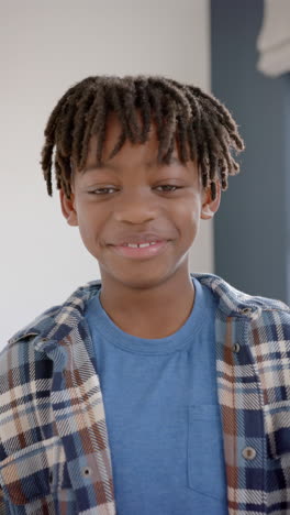 vertical video of portrait of happy african american boy smiling at home, slow motion