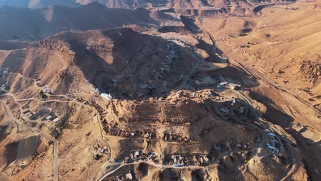 stunning aerial shot of chnenni, tunisia, showcasing its unique hillside architecture and rugged desert landscape.