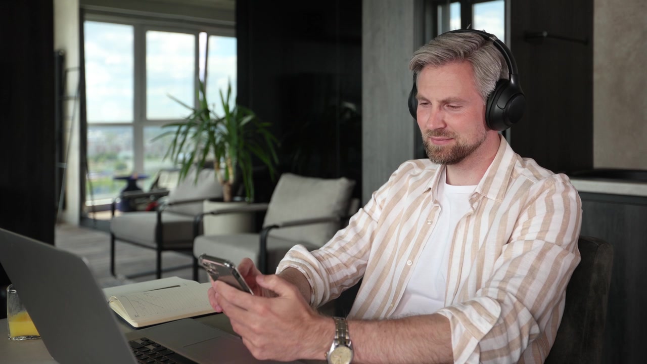 Afslappet mand med hovedtelefoner bruger smartphone derhjemme