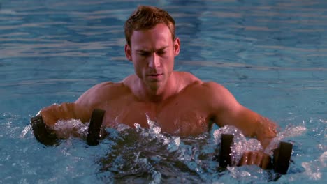 muscular man working out with foam dumbbells in the pool