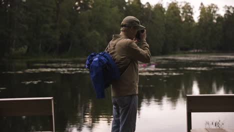 slomo push-in de un fotógrafo masculino tomando fotografías junto al lago en el bosque