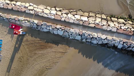 aerial top down view of pier, rocks, sand, beach chairs