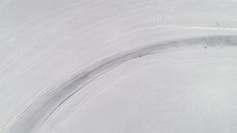 aerial view over an icy race track as a custom utility terrain vehicle zooms around the corner