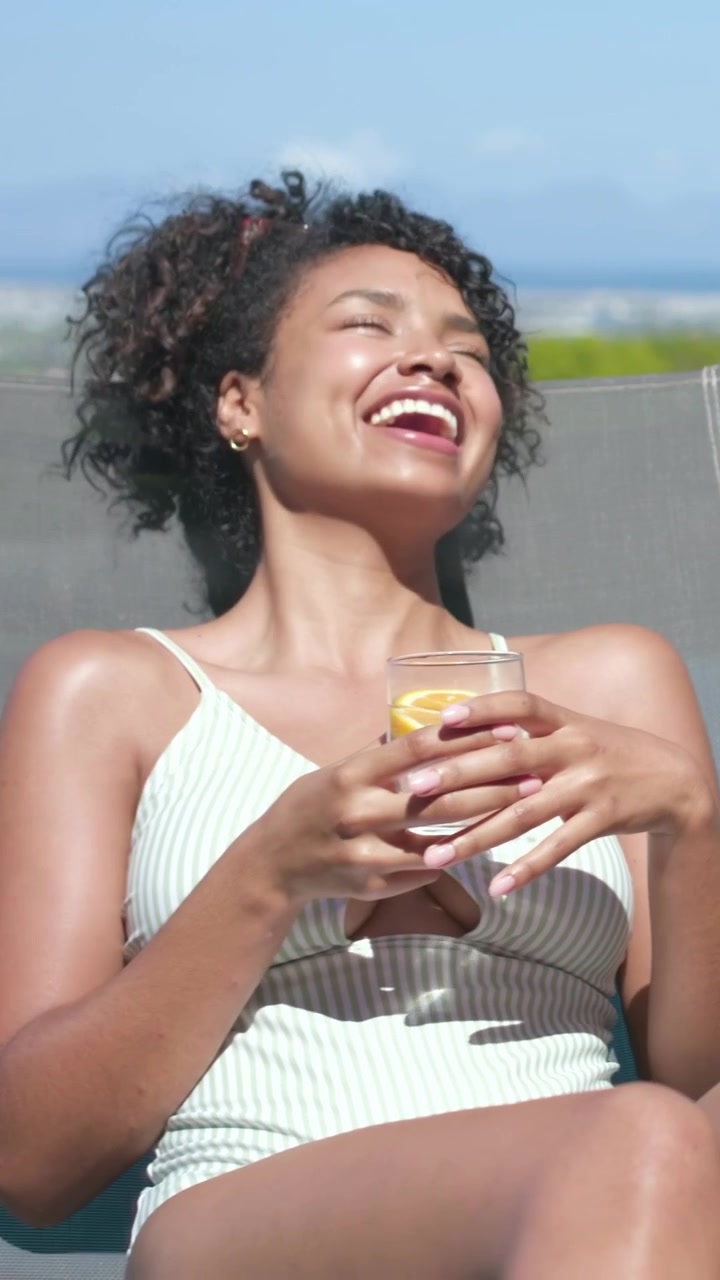 Vertical video: Sipping woman in swimsuit raising glass at pool, sharing toast with shirtless man