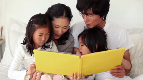 family reading a book as they sit together