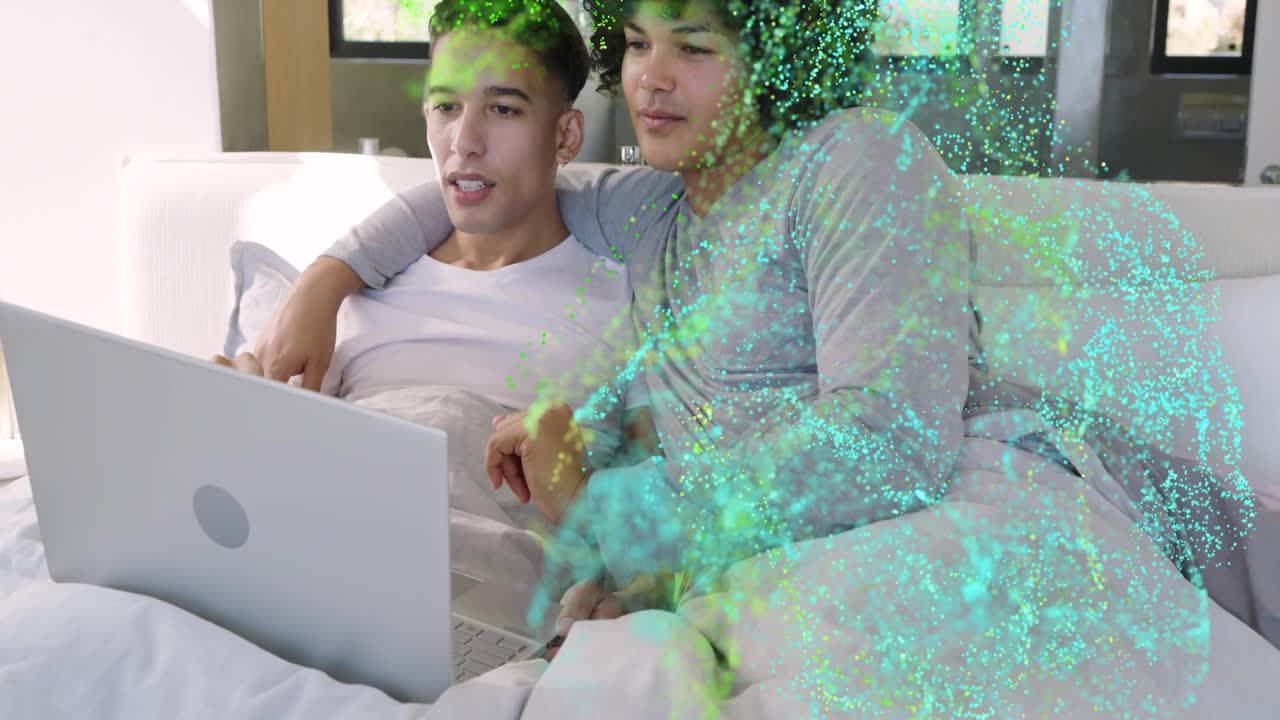 Due uomini seduti, uno che usa il touchpad, che avvia dei punti verde acqua che coprono il laptop, i corpi, testando la tecnologia