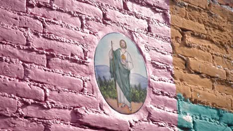 Religious Painting of Jesus on a Pink, Orange, and Green Wall. Footage from San Miguel de Allende, in Mexico. Colorful, shot on a gimbal, and very traditional.