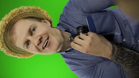 happy man with camera smiling on green screen