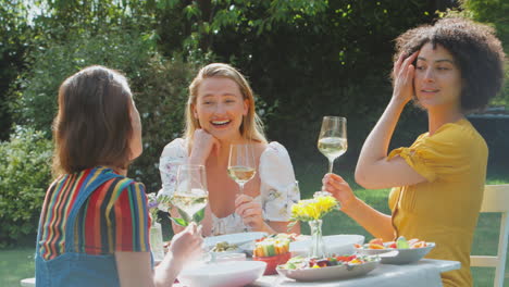 Drei-Freundinnen-Sitzen-Draußen-Im-Sommergarten-Zu-Hause,-Trinken-Wein-Und-Essen