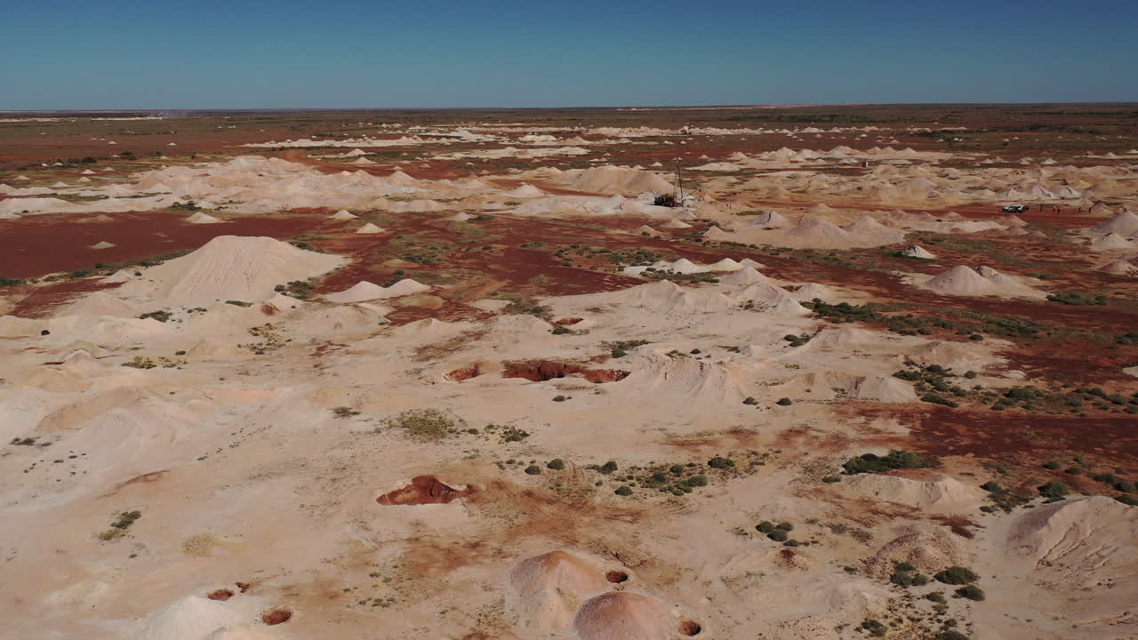aéreo: disparo de un dron volando sobre las minas de opalo hacia grandes máquinas de perforación, en coober pedy, en el interior de australia del sur