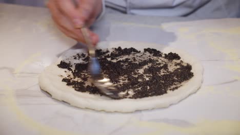 el chef agrega salsa de trufa a la masa de pizza