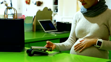 pregnant woman paying bill at counter 4k