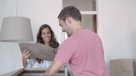 Happy-couple-unpacking-cardboard-boxes-with-stuff,-talking-and-smiling