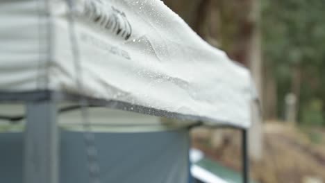 a slow motion handheld shot of light raining falling on a camp gazebo and the water falling down in