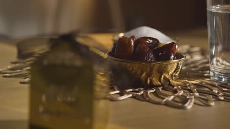 schüssel mit datteln und einem glas wasser auf dem tisch in einem muslimischen haus, das eid 1 feiert