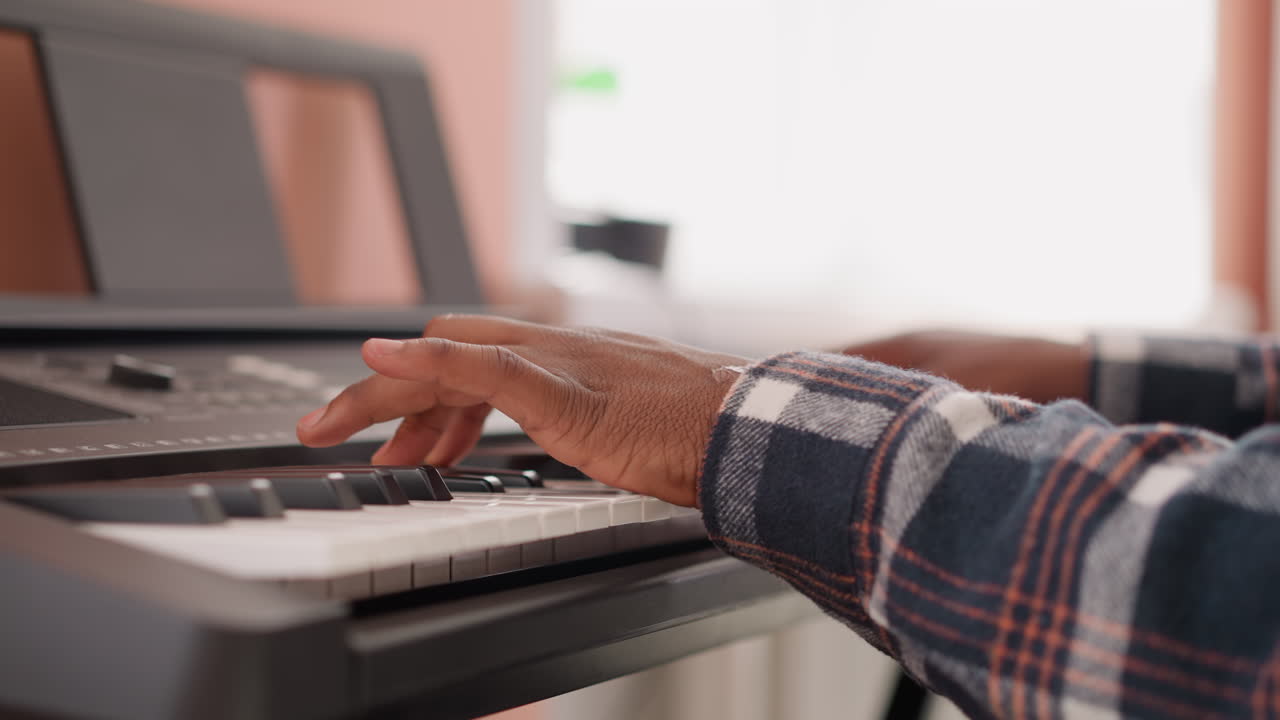 hombre manos en sintetizador teclado primer plano. compositor negro escribe música en instrumento eléctrico en casa. tipo afroamericano aprende a tocar