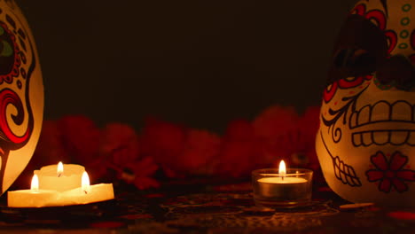 still life of decorated skull masks surrounded by candles and flowers celebrating mexican holiday of dia de muertos or day of the dead against dark background 1