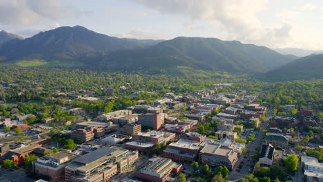 aerial shot of beautiful flatiron mountain vista and bright green trees in downtown boulder colorado during an evening sunset with warm light on the rocky mountain town and summer landscape