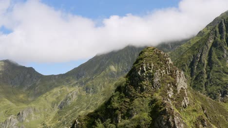 Rocky-peak-in-drone-in-the-Pyrenees,-pass-on-the-other-side-of-the-mountain-to-discover-a-valley