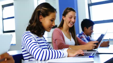 estudiantes que usan tabletas digitales y computadoras portátiles en el aula