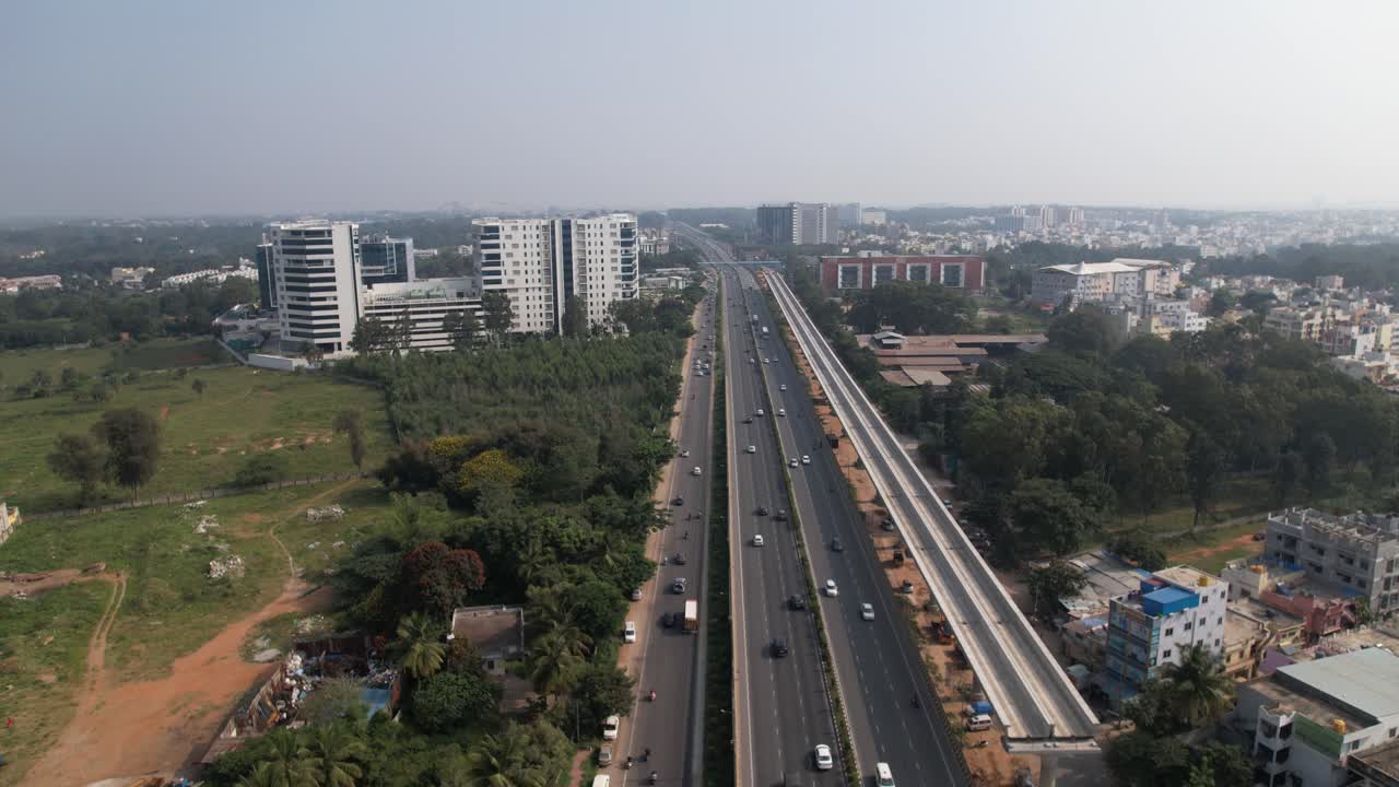 Jalan raya India, sebuah gambar udara dramatis dengan konstruksi jembatan kereta metro terlihat di atas jalan layanan dan mobil-mobil yang melaju cepat.