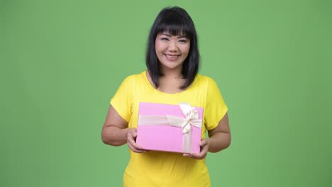 beautiful happy asian woman holding gift box