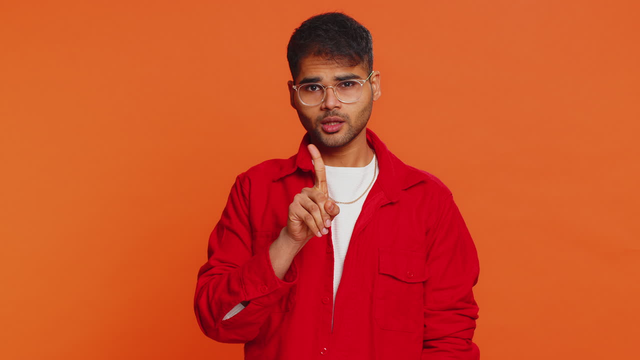 Indian young man shakes finger and saying no be careful avoid danger mistake disapproval sign