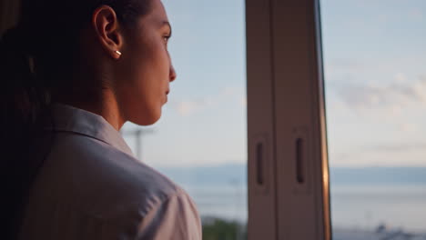 business woman looking out window in hotel room at sunrise planning ahead fresh new day successful independent female contemplating future