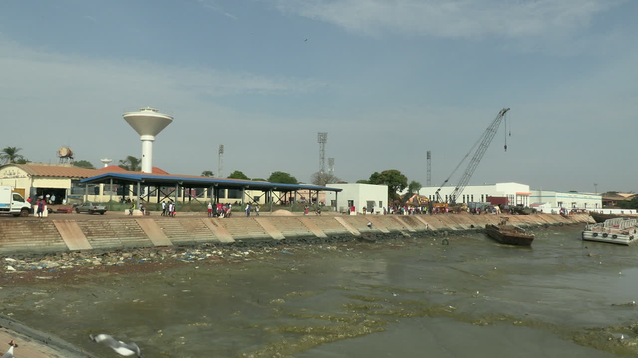puerto pesquero de bandim en marea baja, al fondo la torre de control y una draga que limpia el río